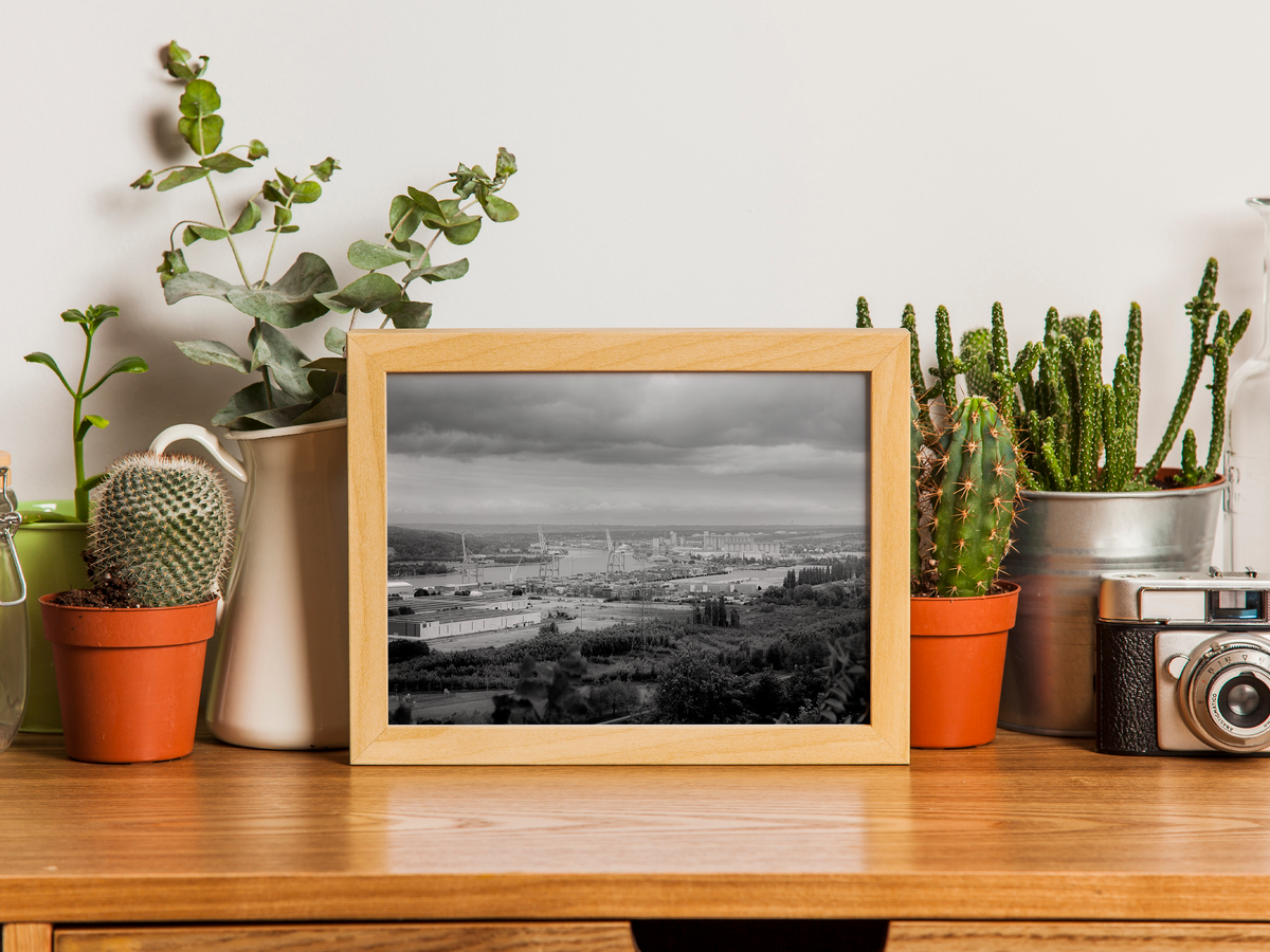 Port de Rouen et boucle de Seine - tirage N&B encadré effet chêne posé sur un bureau avec cactus et appareil photo - Corentin GMT
