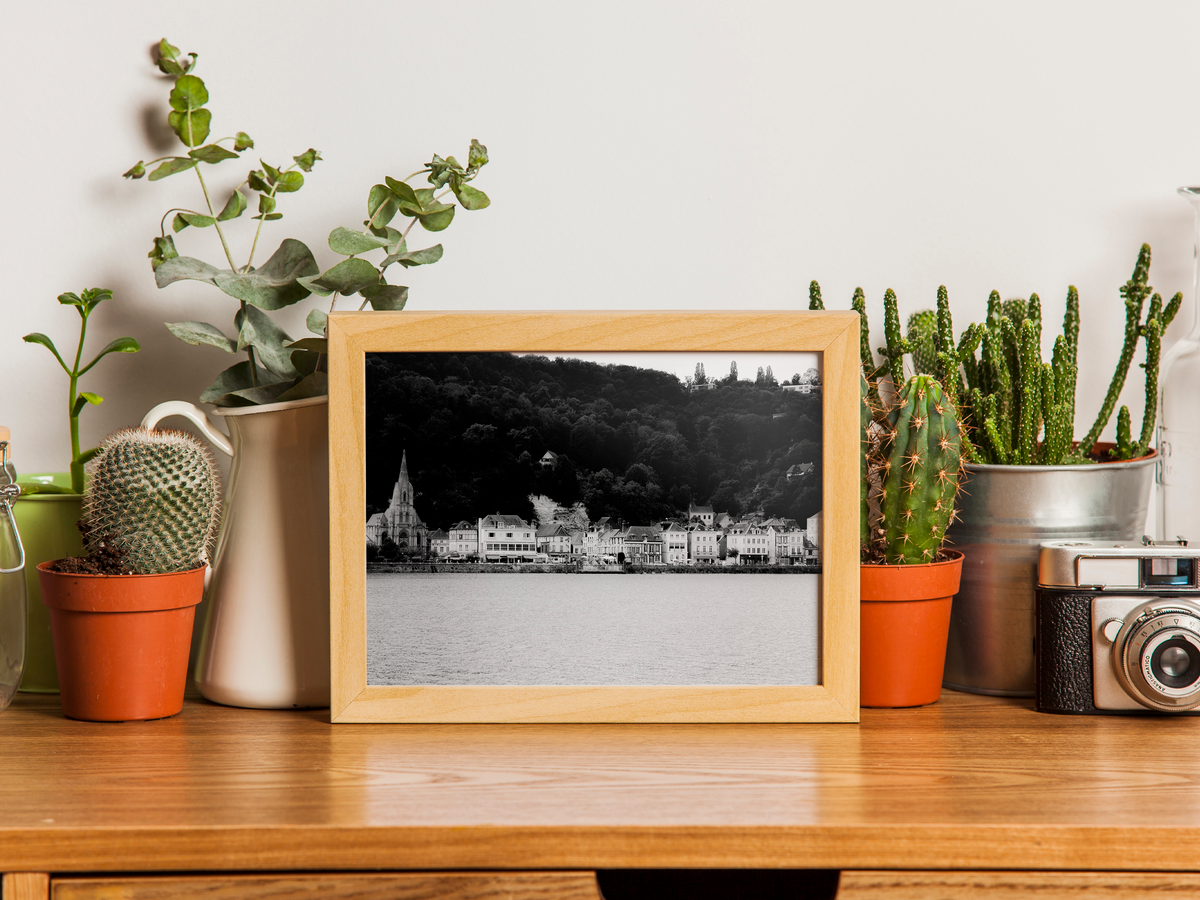 La Bouille vue de la Seine - tirage N&B encadré effet chêne posé sur un bureau avec cactus et appareil photo - Corentin GMT